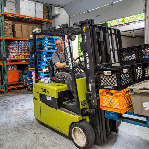 Man removing donated food from a truck using a forklift